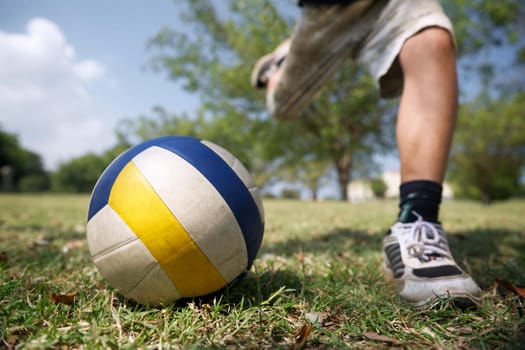 Kids playing football game, young child hitting soccer ball in park
