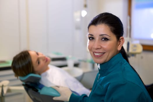 Doctor during visit of woman in dental clinic, portrait of female dentist looking at camera and smiling