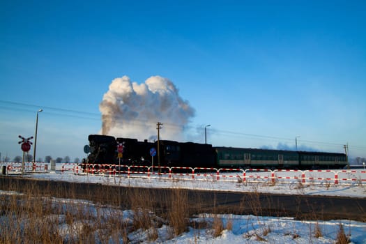 Vintage steam train puffing through countryside during wintertime