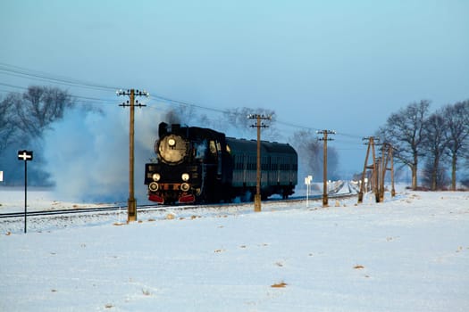 Vintage steam train puffing through countryside during wintertime