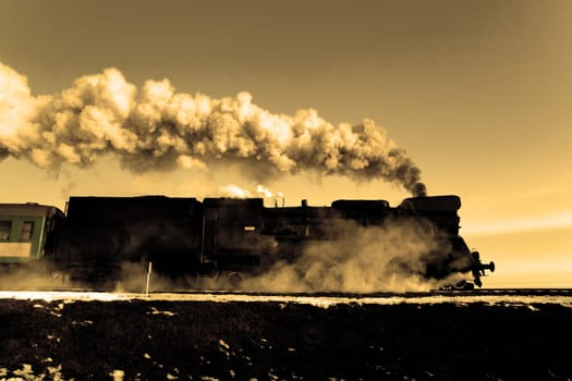 Vintage steam train puffing through countryside during wintertime