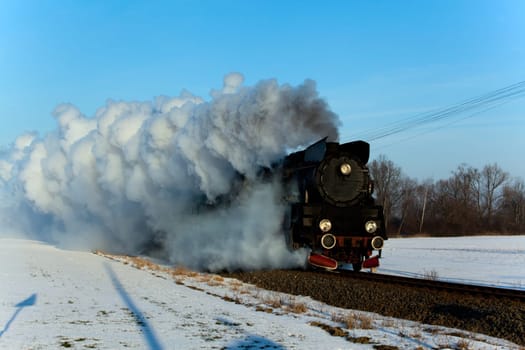 Vintage steam train puffing through countryside during wintertime
