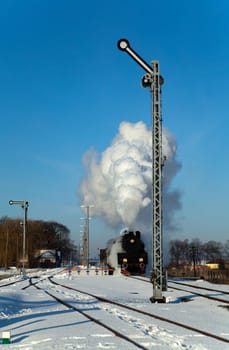Vintage steam train puffing through countryside during wintertime