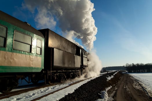 Vintage steam train puffing through countryside during wintertime