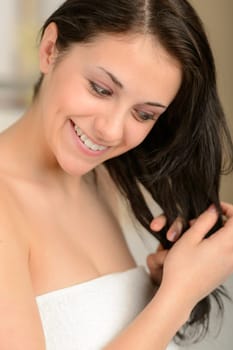 Cheerful young woman styling her hair in the morning