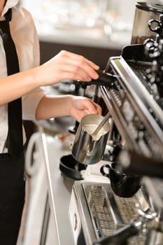Barista steaming milk for hot cappuccino with machine