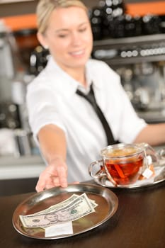 Attractive waitress taking tip in bar from tray american dollar