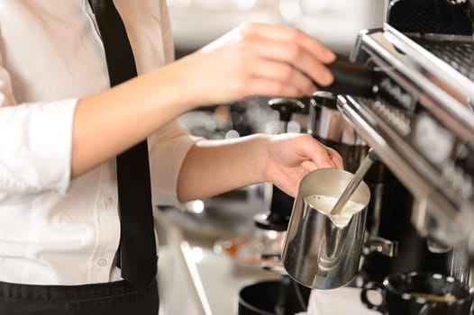 Barista steaming milk for hot cappuccino with machine