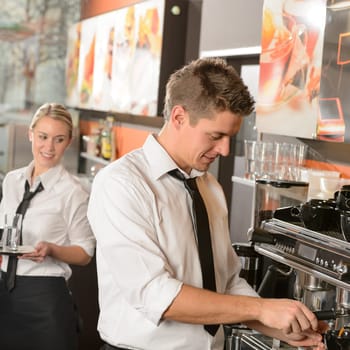 Young waiter and waitress working in bar serving coffee