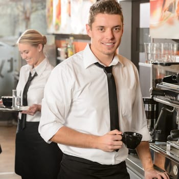 Handsome waiter making coffee with espresso machine in coffee house