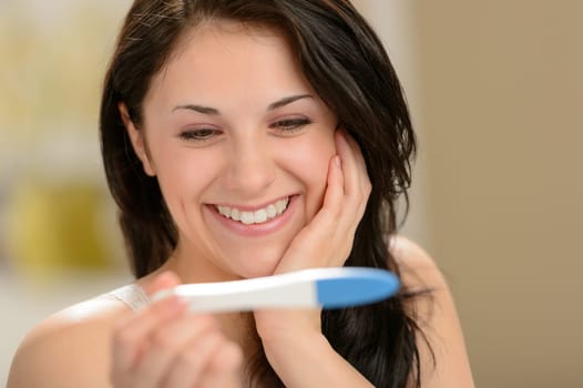 Delighted and surprised woman holding pregnancy test