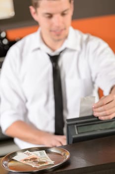 Young bartender in uniform taking cash czech crowns in bar