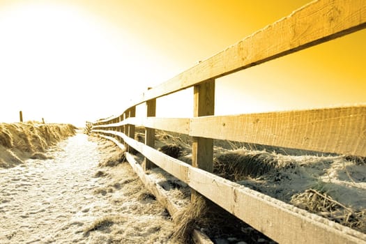 frosty winters view at ballybunion cliffside walk with bright sunset and fence