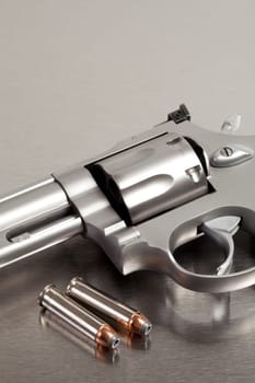Handgun with bullets - modern revolver on brushed metal with two bullets