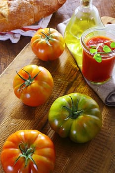 Preparing fresh tomato paste for use as an ingredient in Italian cooking with fresh whole tomatoes and olive oil on a wooden kitchen table