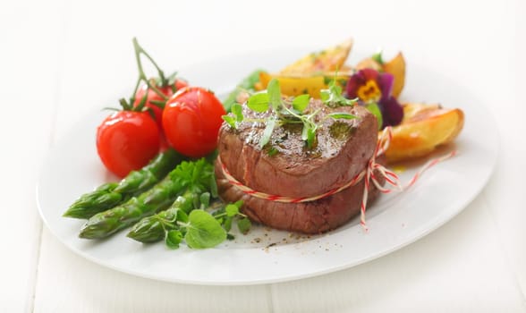 Delicious thick portion of grilled fillet steak served with fresh green asparagus spears, potato and tomato