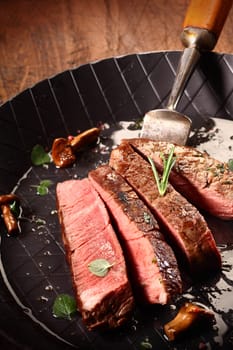 Rare cooked lean beef steak or fillet sliced through in a roasting pan during the cooking and preparation of a gourmet meal