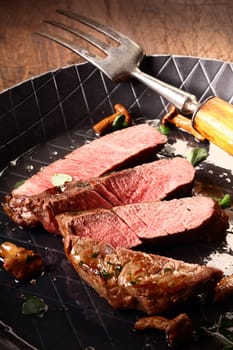 Pan roasted rare beef steak sliced through to expose the delicious pink meat waiting in the skillet to be served for a healthy meal