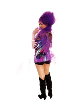 A young tall woman standing for white background in black shorts and long boots with lilac twill around her head.