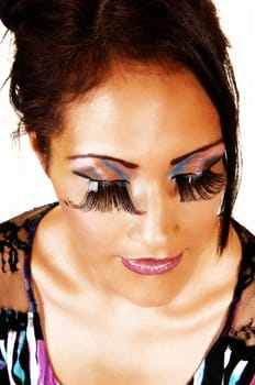 A very pretty face of a young woman with lovely makeup and long eyelashes and red lips in a closeup shoot with her eyes closed.