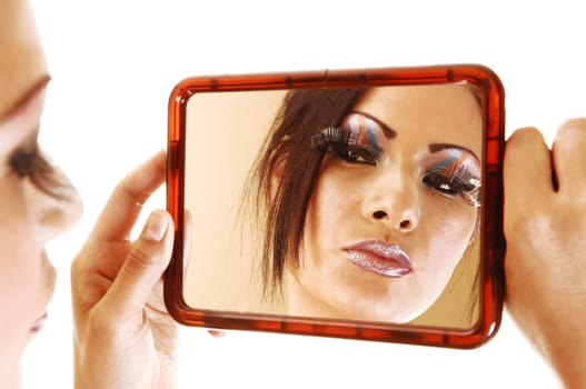 A young pretty woman holding up a mirror looking at her makeup with long eyelashes and nice makeup for white background.