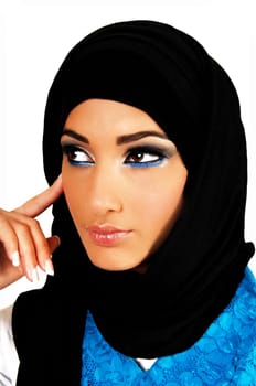 A pretty and young teen girl with a black headscarf and nice makeup looking into the camera with one finger on her face for white background.