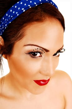 A closeup heat shoot of a gorgeous woman with long eyelashes and red lips and a blue headband in her hair.