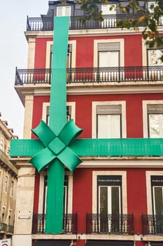 Lisbon, Portugal - 29.12.2022: A vibrant green ribbon decorates a charming red building, significantly enhancing its festive appeal