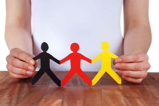 hand holds paper chain people in the color of germany, isolated