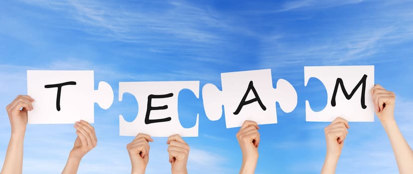 hands holding four pieces of a puzzle with copy space, sky background