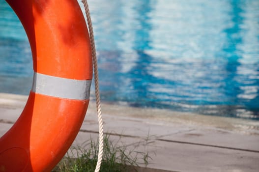 orange red ring-buoy with pool in background