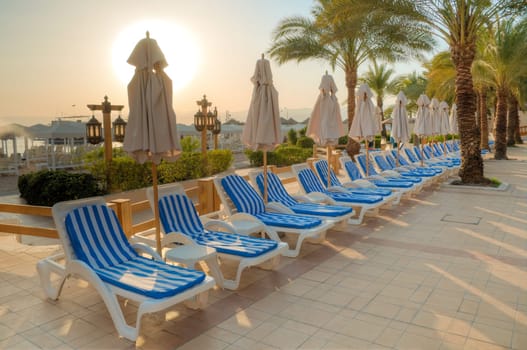 sunset over empty beach lounge at tropical resort