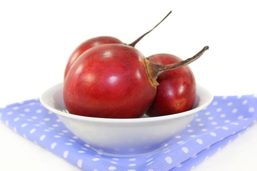 three red tamarillos against white background