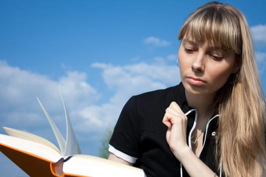 girl standing with book outdoor with sky in background