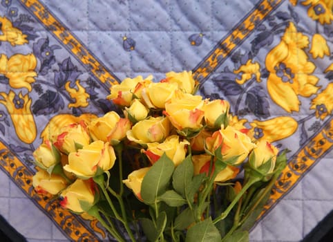 miniature yellow roses on a blue and yellow quilted fabric