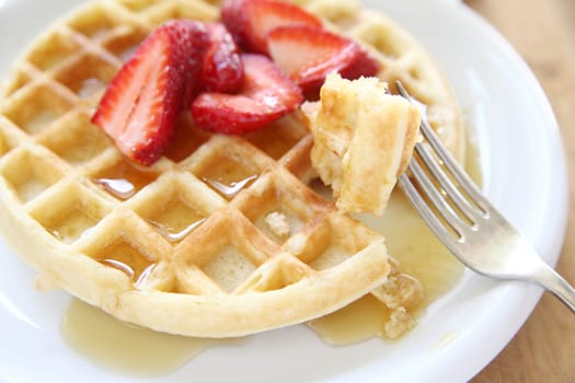 large breakfast waffle with fresh strawberries and syrup