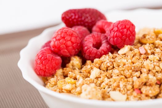 Zoomed berries on golden cereals in white bowl