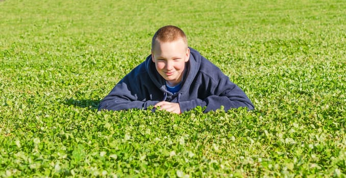Handsome lying kid rest on the fresh spring grass