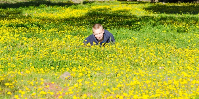 Attractive resting kid lay on the fresh spring meadow