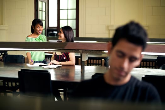 Young people at school, male and female students studying and doing homework in university library