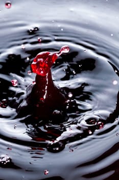 Close view of a droplet of wine hitting a surface of wine.