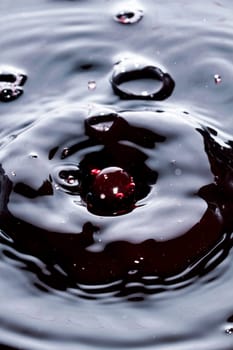 Close view of a droplet of wine hitting a surface of wine.