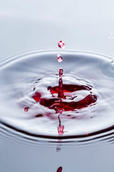Close view of a droplet of wine hitting a surface of wine.
