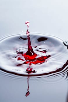 Close view of a droplet of wine hitting a surface of wine.