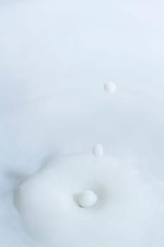 Close view of a droplet of milk hitting a surface of milk.