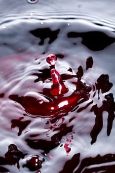 Close view of a droplet of wine hitting a surface of wine.