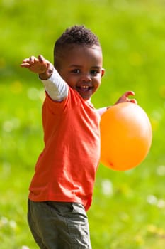 Outdoor portrait of a cute young  little black boy playing with a balloon - African people