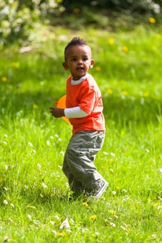 Outdoor portrait of a cute young  little black boy playing with a balloon - African people