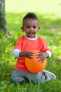 Outdoor portrait of a cute young  little black boy playing with a balloon - African people