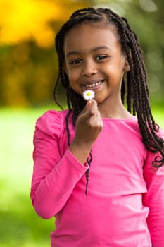 Outdoor portrait of a cute young black girl holding a dandelion flower - African people